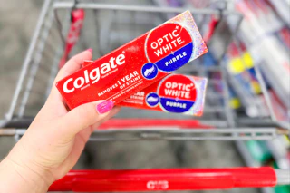 person holding 2 colgate toothpastes over a cart
