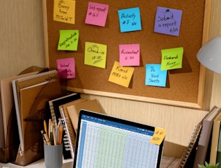 sticky notes on a board at a desk with a laptop