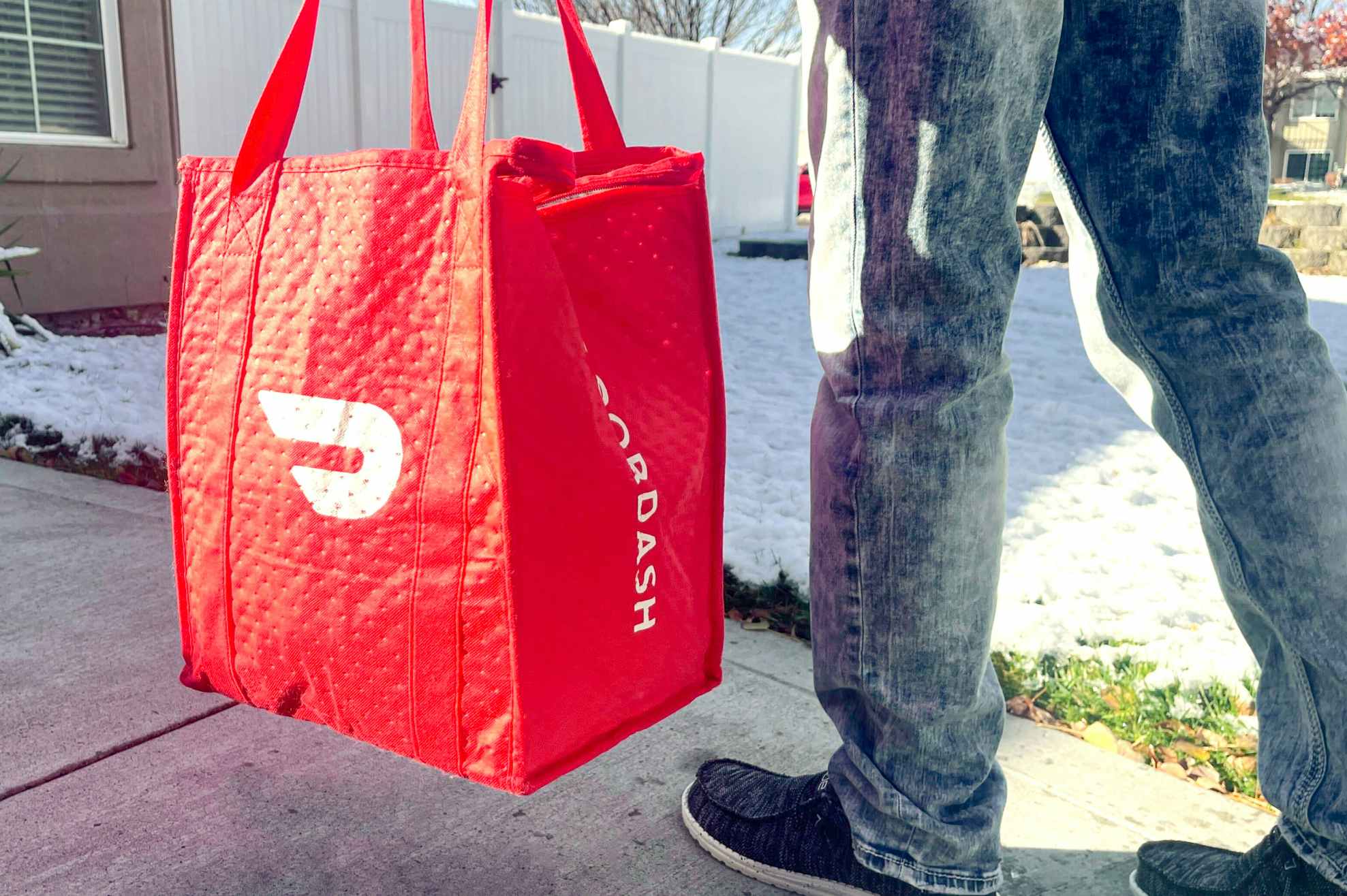 person walking while holding Doordash food delivery bag