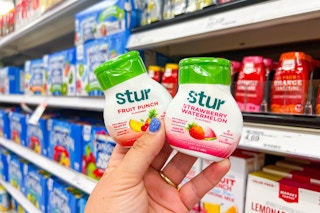 Hand holding 2 flavors of Stur drink mix
