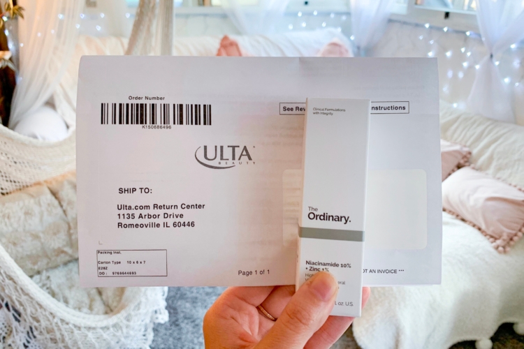Hand holding a box of The Ordinary skin care product and an online Ulta order receipt.