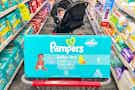 pampers diaper box in a shopping cart with a baby in a stroller in the background