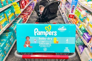pampers diaper box in a shopping cart with a baby in a stroller in the background
