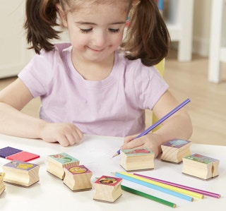 A girl decorating paper with colored pencils and stamps