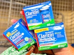 hand holding claritin allergy care products over a shopping cart
