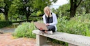 a college student on their laptop sitting outside