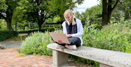 a college student on their laptop sitting outside