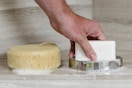 a hand on a bar of soap in a soap dish next to a sponge