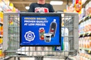 a close up of the front of a kroger shopping cart with person pushing it in the background 