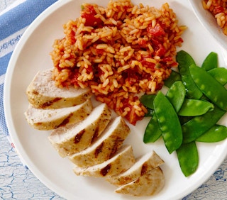 Rice, chicken strips, and a salad on a white plate