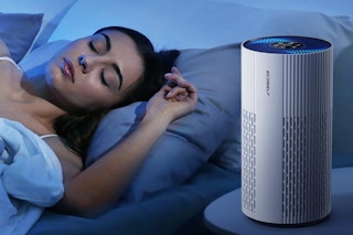 a woman sleeping next to an air purifier