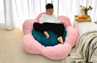 Lifestyle image of a kid on a flower-shaped bean bag cushion