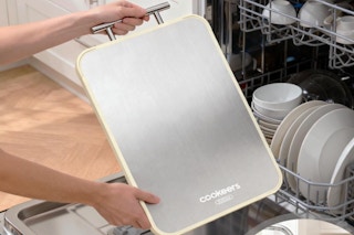 Person holding the COOKEERS Stainless Steel Cutting Board by a dish washing machine.