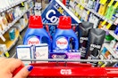 person pushing a cart with cottonelle toilet paper, persil detergent, secret deodorant, crest toothpaste, and axe body wash