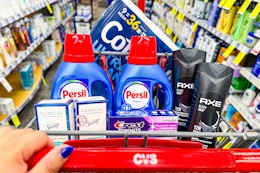 person pushing a cart with cottonelle toilet paper, persil detergent, secret deodorant, crest toothpaste, and axe body wash