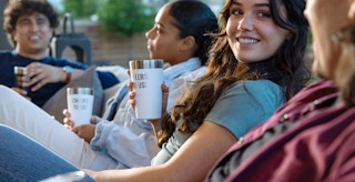 friends sitting outside and holding custom engraved stanley cups