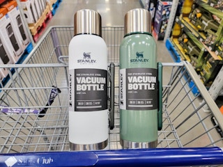 a white and a green stanley insulated vacuum bottle in a cart
