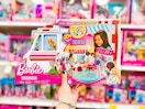 hand holding a barbie clinic and ambulance in front of a target shelf