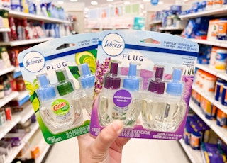 hand holding two packs of febreze plug refills