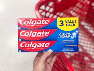 hand holding a 3 pack of colgate cavity protection toothpaste at target