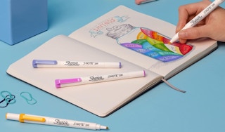 colorful markers on a notebook with a drawing