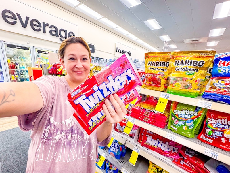 person taking a selfie with 2 bags of twizzlers candy