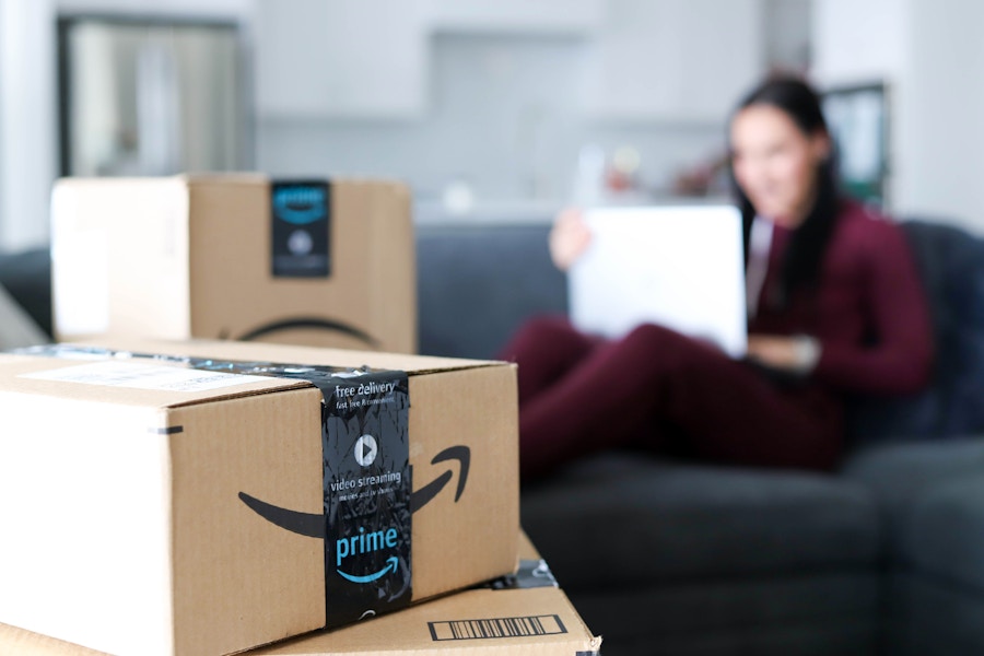 someone on their laptop in a livingroom with amazon boxes