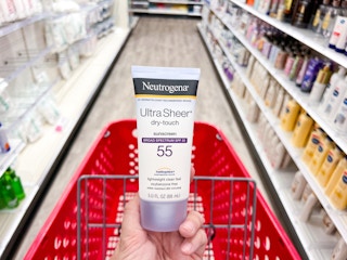hand holding Neutrogena sunscreen in middle of Target aisle