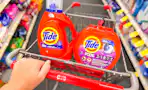 person pushing a cart with tide pods and liquid detergent in it