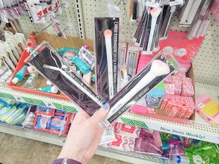 hand holding 3 wet n wild makeup brushes
