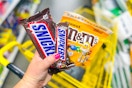 hand holding snickers candy next to m&m's