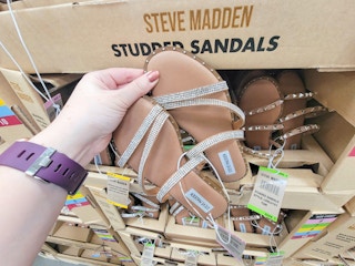 hand holding a pair of tan studded sandals