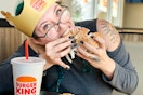 a woman wearing a burger king crown eating a whopper