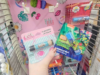 hand holding a lol surprise and ninja turtles lip balms