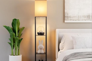 a floor lamp with shelves next to a bed