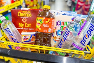 cheerios, cinnamon toast crunch, propel, fritos, lipton products in a yellow shopping cart