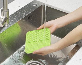 a green pet licking treat mat being washed