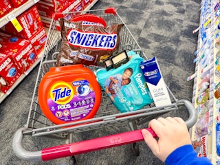 snickers candy, tide pods, maybelline eyeshadow, pampers baby wipes, and crest gum toothpaste in a cart
