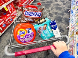 snickers candy, tide pods, maybelline eyeshadow, pampers baby wipes, and crest gum toothpaste in a cart