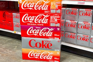 stack of coca cola soda 12 packs on store floor