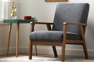 An accent chair with wood frame sits next to a table.