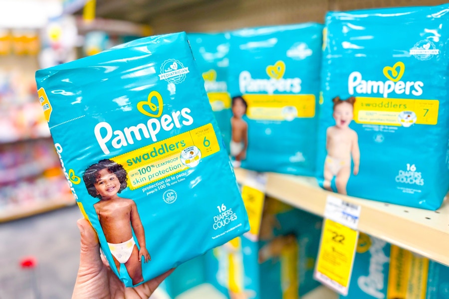 person holding a package of pampers diapers by the shelf with more diapers