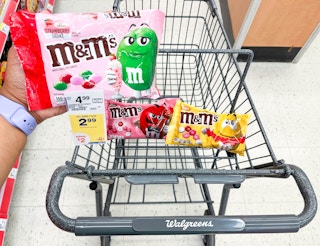 hand holding M&M's Valentine's Day candy bag in front of shopping cart with two more bags