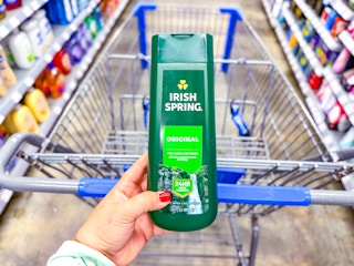 hand holding a bottle of irish-spring-body-wash in front of walmart cart