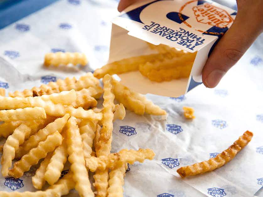 White castle french fries being poured out of the cardboard container onto a serving tray