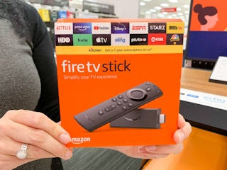 A person holding up an Amazon Fire TV Stick inside of a store.