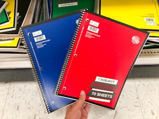 hand holding notebooks in front of store shelf