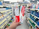 hand holding colgate toothpaste and toothbrush in walgreens