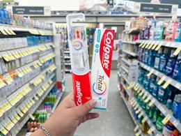 hand holding colgate toothpaste and toothbrush in walgreens