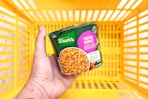 hand holding a knorr pasta cup above a yellow shopping basket